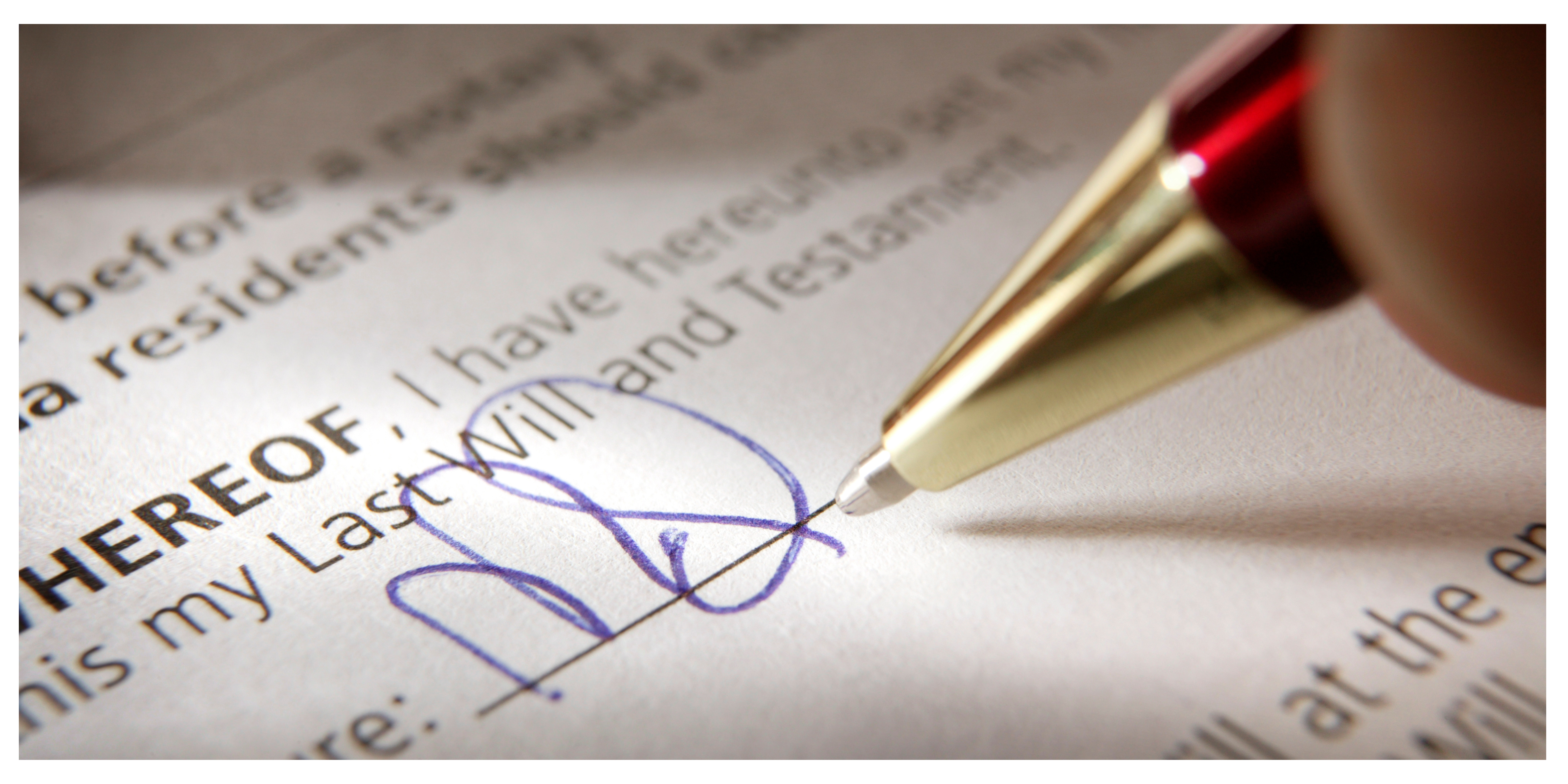 Will being signed. Hand holding a pen while signing a legal will.