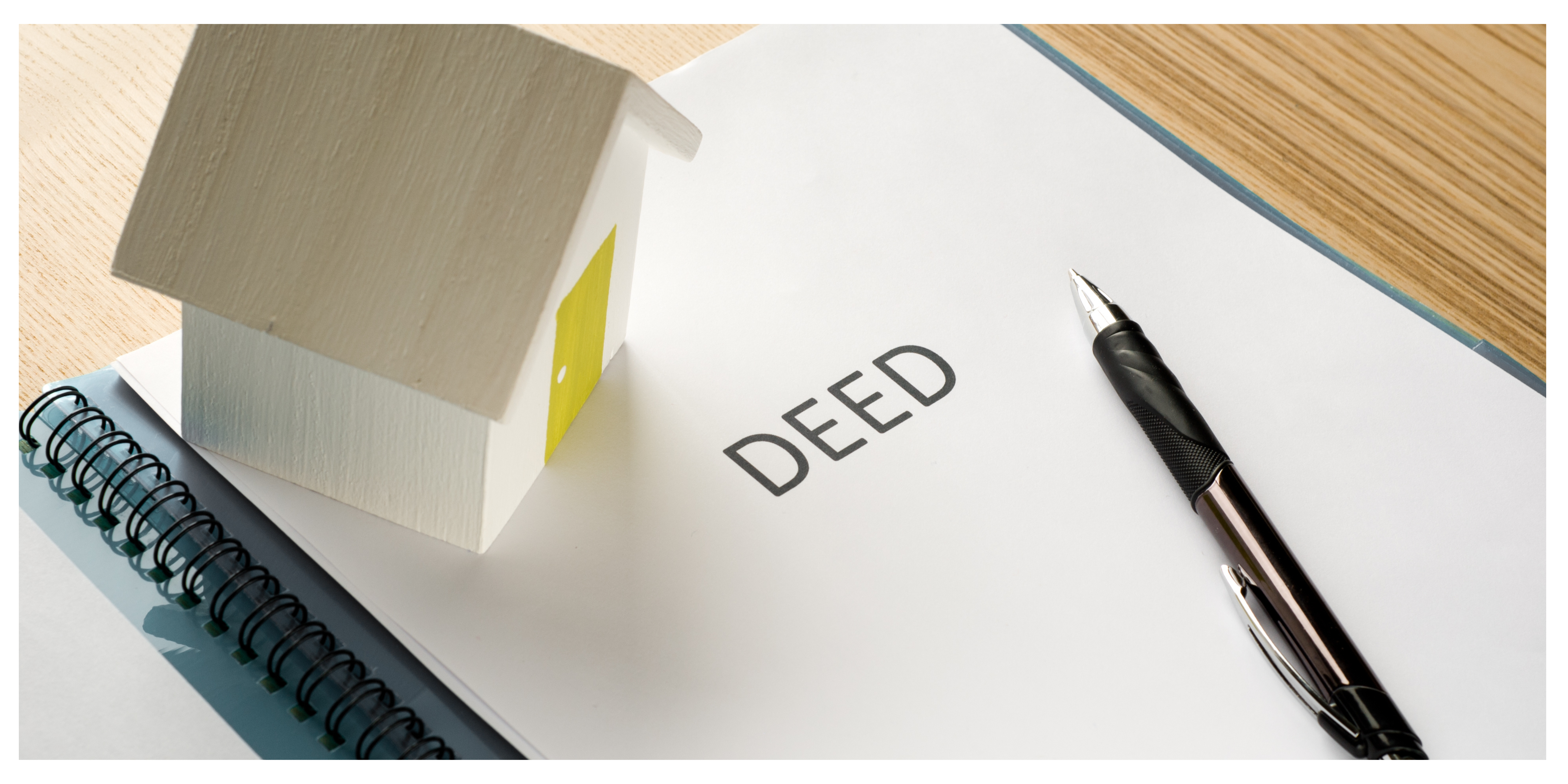 Deed and House Model A paper labeled ‘Deed’ with a small model house and a pen placed on top.